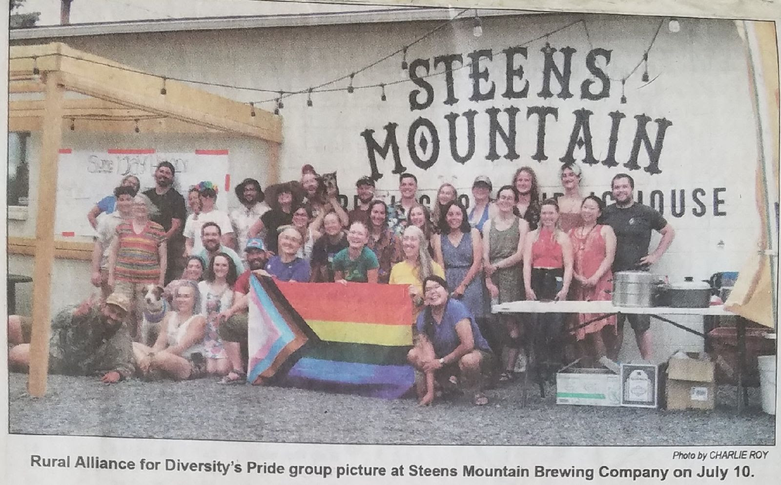 A group of about 50 people gathered at Steens Mountain Brewing holding a Pride Flag