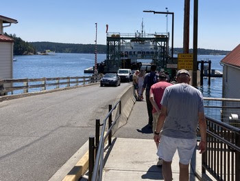 People walking toward a ferry while vehicles disembark the vessel at Orcas terminal