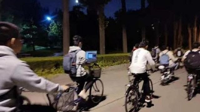 Em uma das fotos, um estudante da Universidade de Tsinghua usava seu laptop enquanto andava de bicicleta