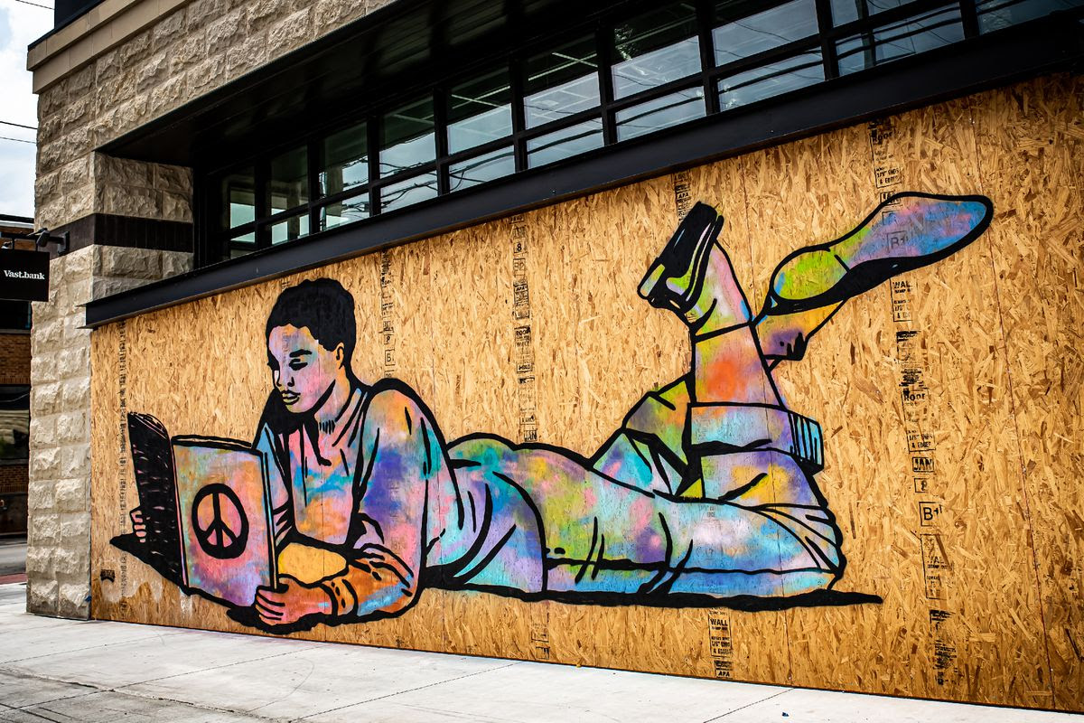 Graffiti of a young woman reading a book while lying on her front with her feet up.