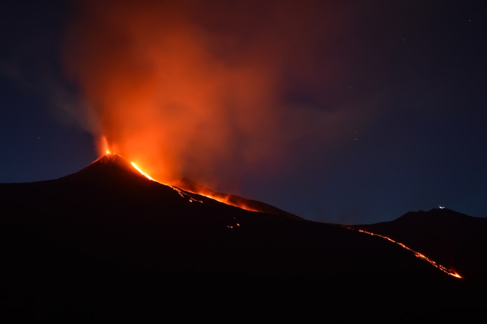 montagna nera con lava che scorre di notte