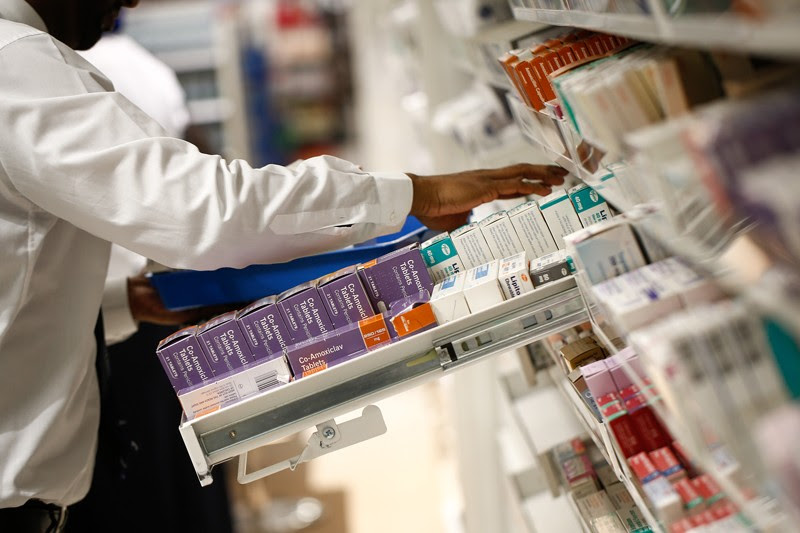 A pharmacist looks through a draw of boxed medications