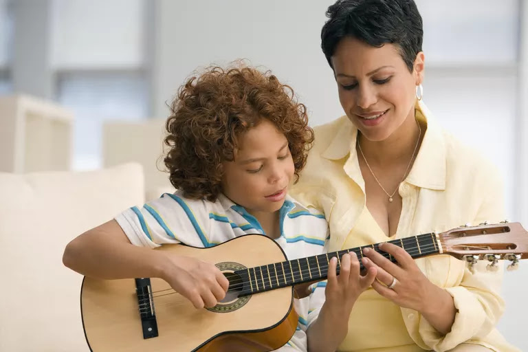 Mother showing son how to play guitar