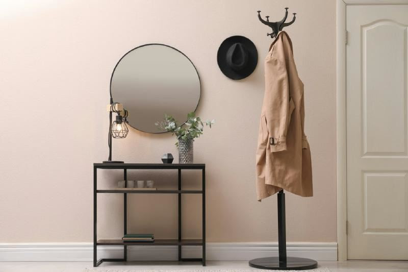 A coat rack and a round mirror Description automatically generated