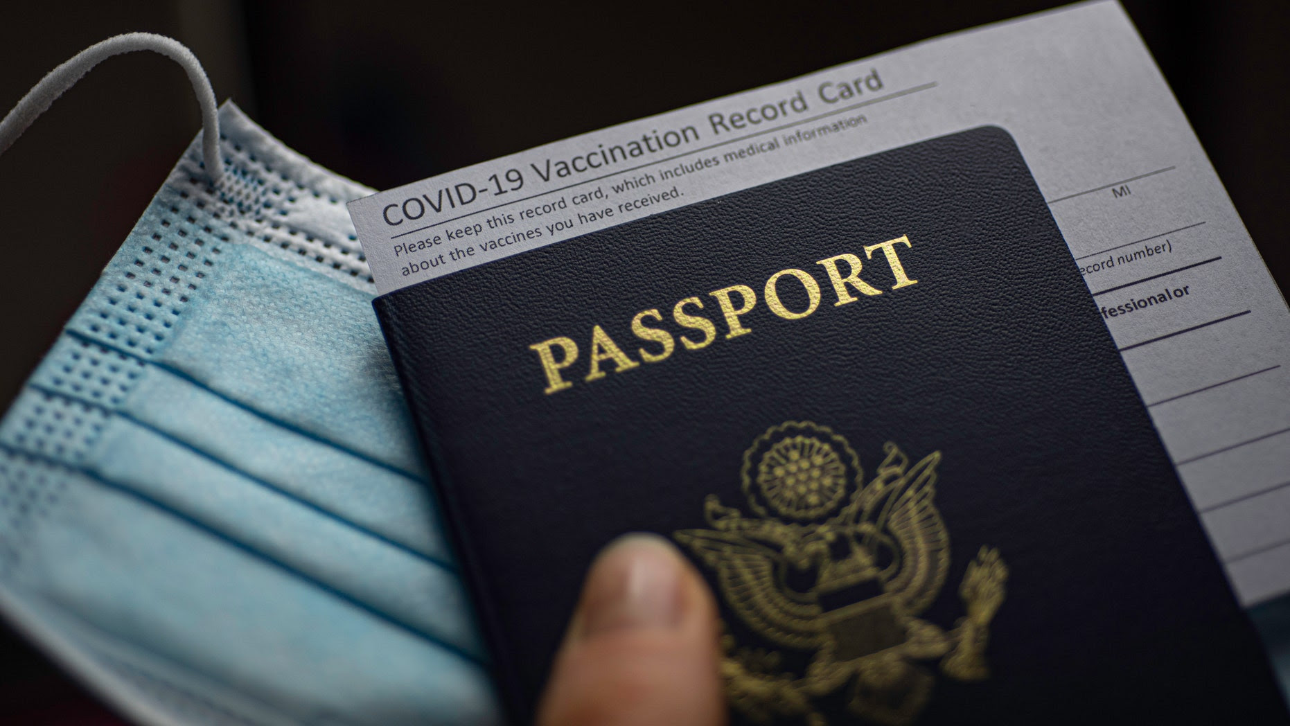 Vaccine card stuck into a passport on a mask