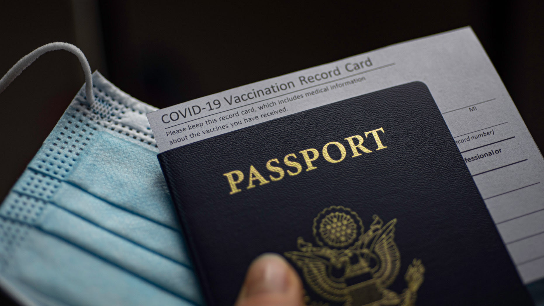 Vaccine card stuck into a passport on a mask