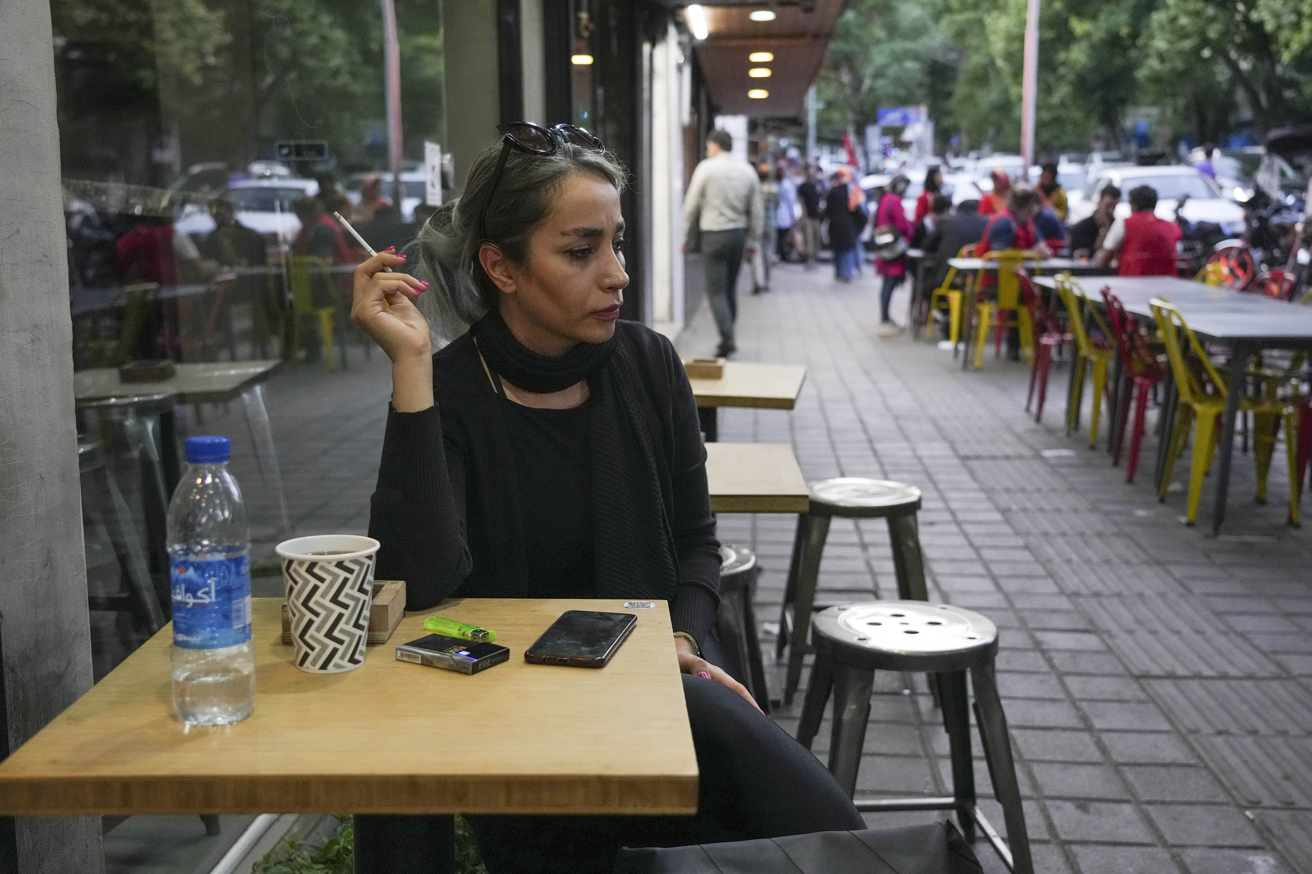 A woman sits in the alfresco dining area of a cafe at Tajrish commercial district without wearing her mandatory Islamic headscarf in northern Tehran, Iran