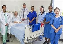 photo of six doctors standing next to a hospital patient