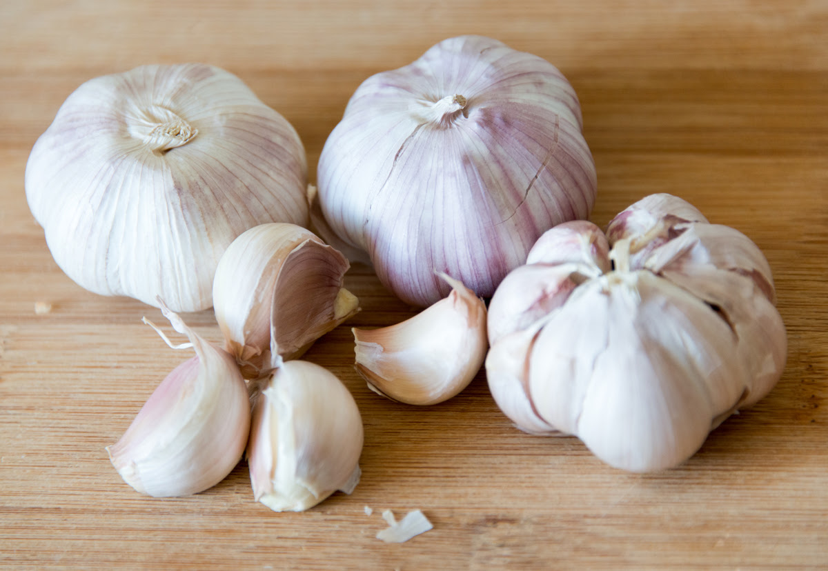 Garlic cloves sits on a wooden cutting board