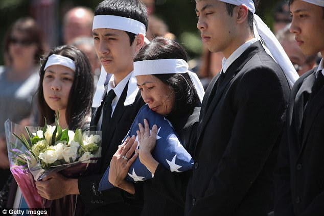 Myhanh Best, Ricky's wife, clutches the flag that draped his casket during a committal service on Monday
