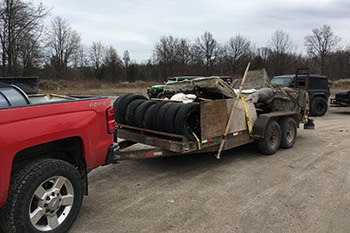 red truck hauling trailer full of tires and other trash