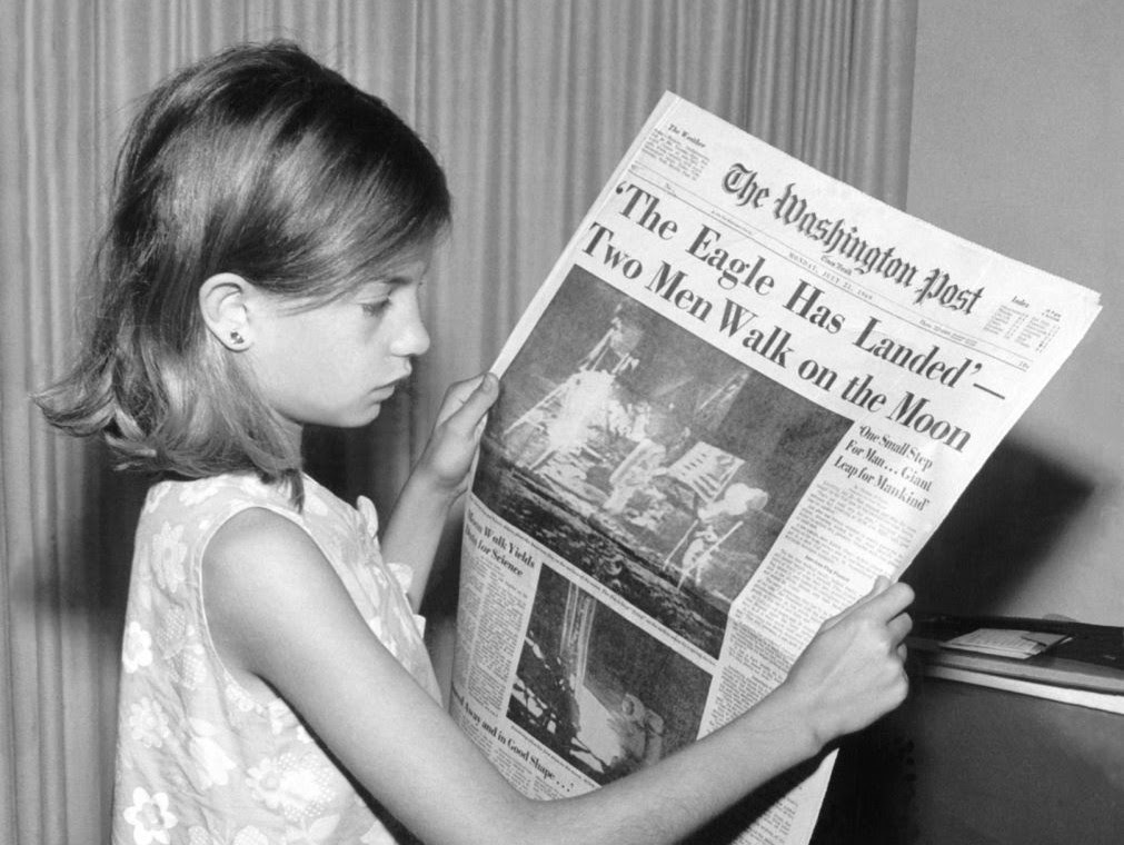 Une fillette lit un journal.