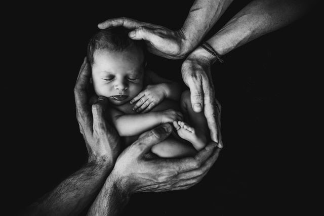 baby surrounded by hands.jpg