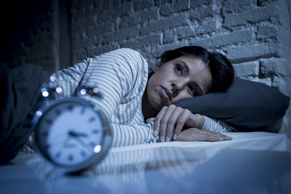 woman lying in bed with alarm clock