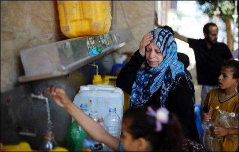 Los palestinos llenan botellas y recipientes con agua de una fuente pública en Rafah, en el sur de la Franja de Gaza.