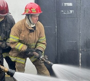 Patty Rubstello using a fire hose to shoot water