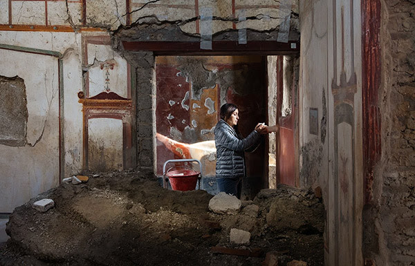 In this picture from January, Arianna Traviglia stands in a shaft of light in the partly ruined structure called the House of the Painters at Work. She is holding a colorimeter, a device that helps me to determine and specify the original colours in the frescoes.