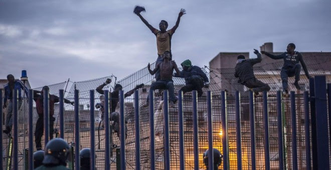 Inmigrantes subsaharianos encaramados a la valla de Melilla.- AFP
