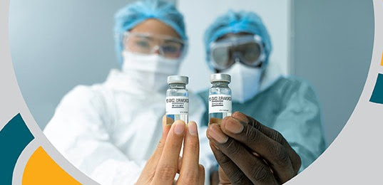 image of two lab workers in ppe holding vaccine bottles forward