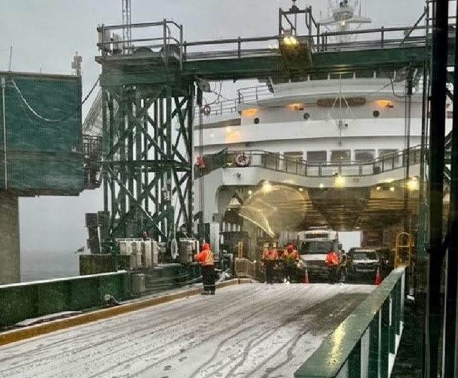 Ferry docked at terminal in snowy conditions with terminal staff and vessel crew working to secure the vessel