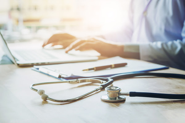 Doctor typing information on laptop in hospital office focus
