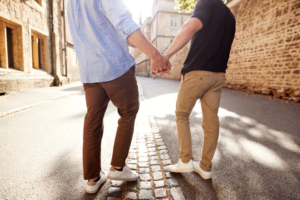 two men walking on the street holding hands