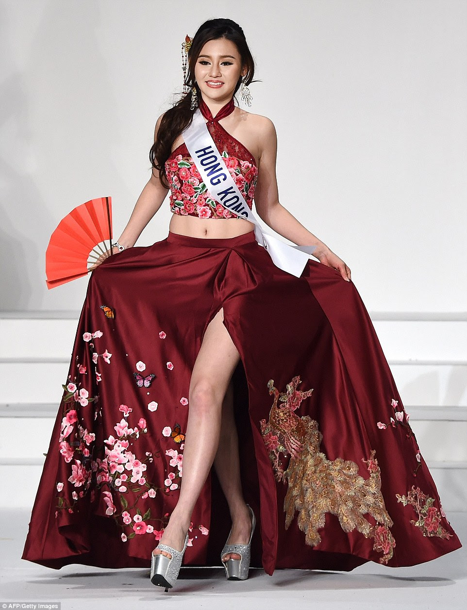 Sabrina Yeung represented Hong Kong with a beautiful maroon silk skirt embroidered with cherry blossom - which blooms in the country's parks and streets come spring time - and a Chinese dragon. With sky-high sparkly silver platforms and holding a red fan, she also wore a floral halterneck crop top and intricate comb in her hair. 