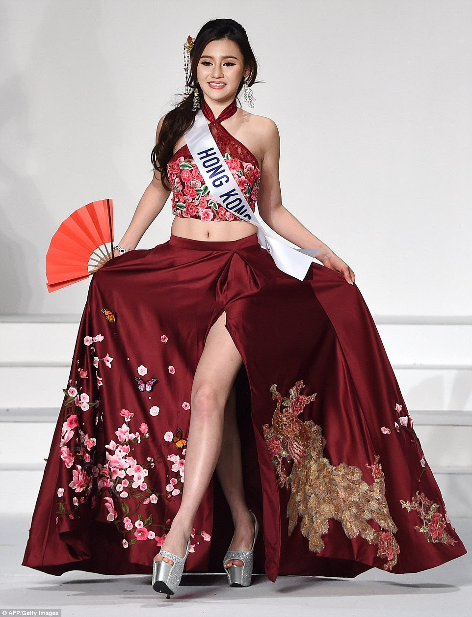 Sabrina Yeung represented Hong Kong with a beautiful maroon silk skirt embroidered with cherry blossom - which blooms in the country's parks and streets come spring time - and a Chinese dragon. With sky-high sparkly silver platforms and holding a red fan, she also wore a floral halterneck crop top and intricate comb in her hair.