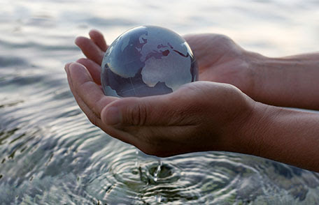 Manos sosteniendo un globo de cristal sobre el agua