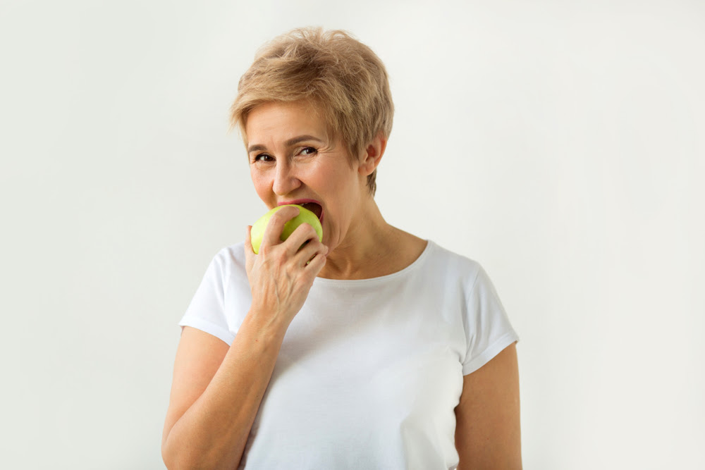 older woman eating an apple