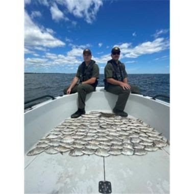 two ECOs sit at front of small boad with 100 illegally caught fish on the deck