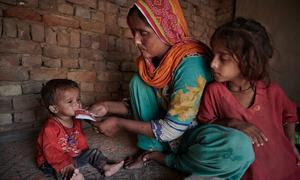 Una madre alimenta a un niño desnutrido en su casa, en un pueblo devastado por las inundaciones en Pakistán