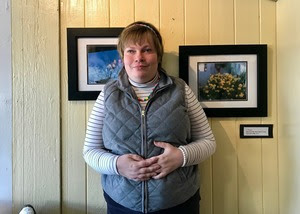 A student stands in front of her artwork on display at Penny Cluse Cafe in Burlington.