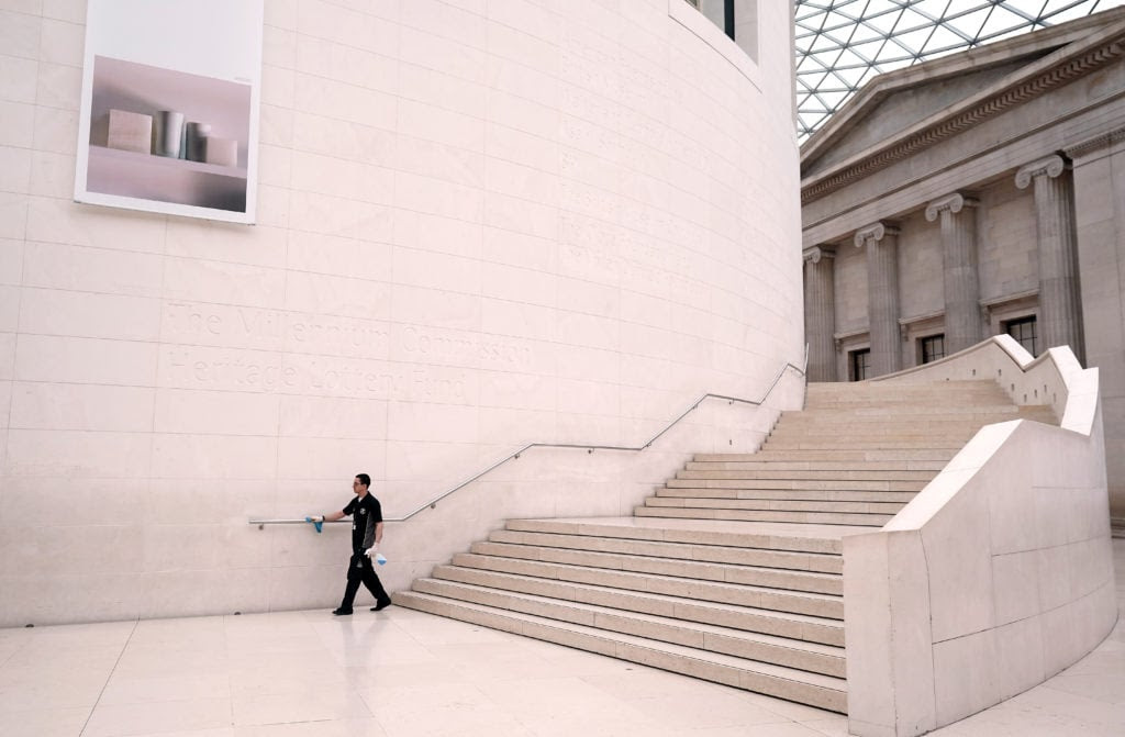 A cleaner wipes down the handrails in the British Museum the day after Prime Minister Boris Johnson called on people to stay home and avoid all non-essential contacts and travel in order to reduce the impact of the coronavirus pandemic. Photo by John Walton/PA Images via Getty Images.
