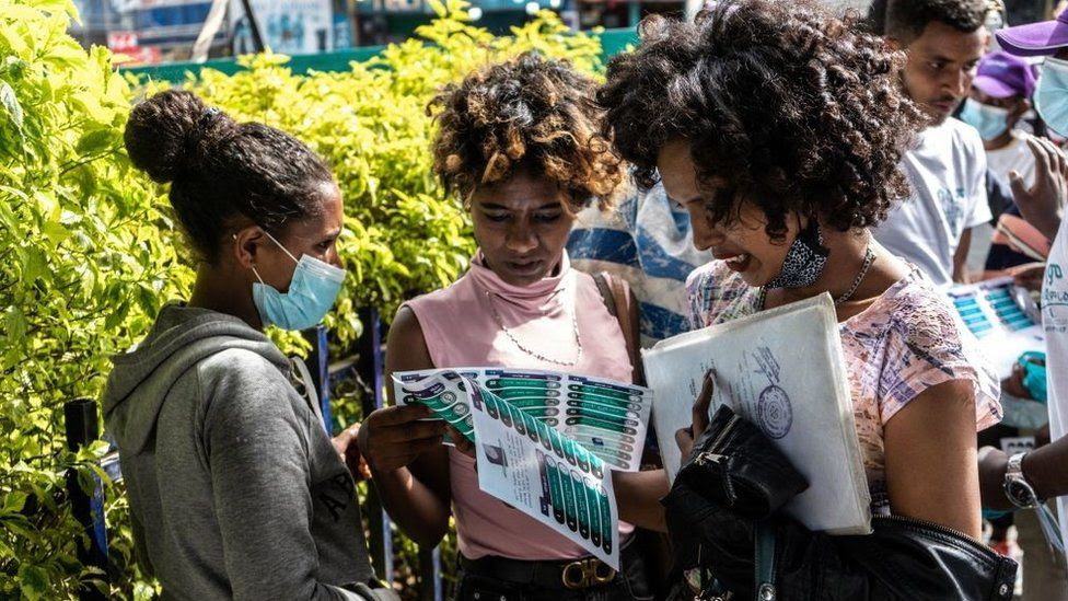People hold a paper that shows a list of political parties in Addis Ababa, Ethiopia, on June 17, 2021, who are running for the upcoming June 21, 2021 elections
