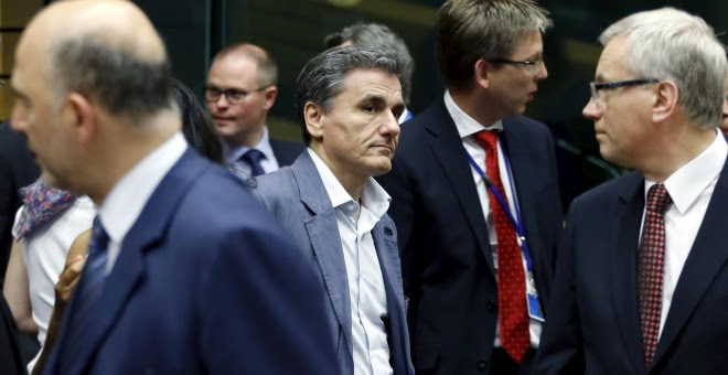 Greek Finance Minister Euclid Tsakalotos walks past Lithuanian counterpart Rimantas Sadzius (R) and European Economic and Financial Affairs Commissioner Pierre Moscovici (L) during an euro zone finance ministers meeting in Brussels, Belgium, July 11, 2015