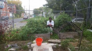 Tool Library member Danyell Brent kneels beside his veggie beds that he built with tools from the library.