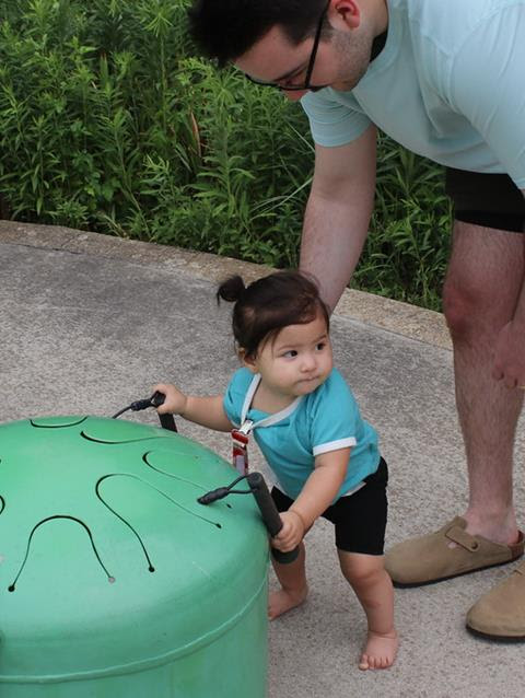 child with dad playing on equipment in sound garden