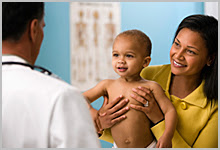 Mother holding a happy baby and talking with a doctor.