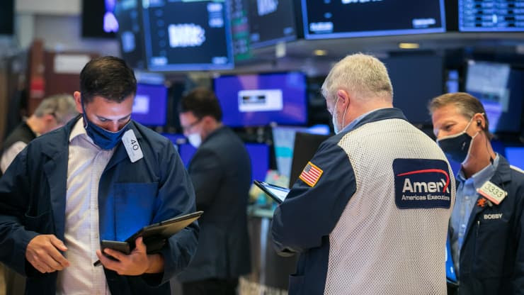 Traders look down at their devices as they stand in a circle