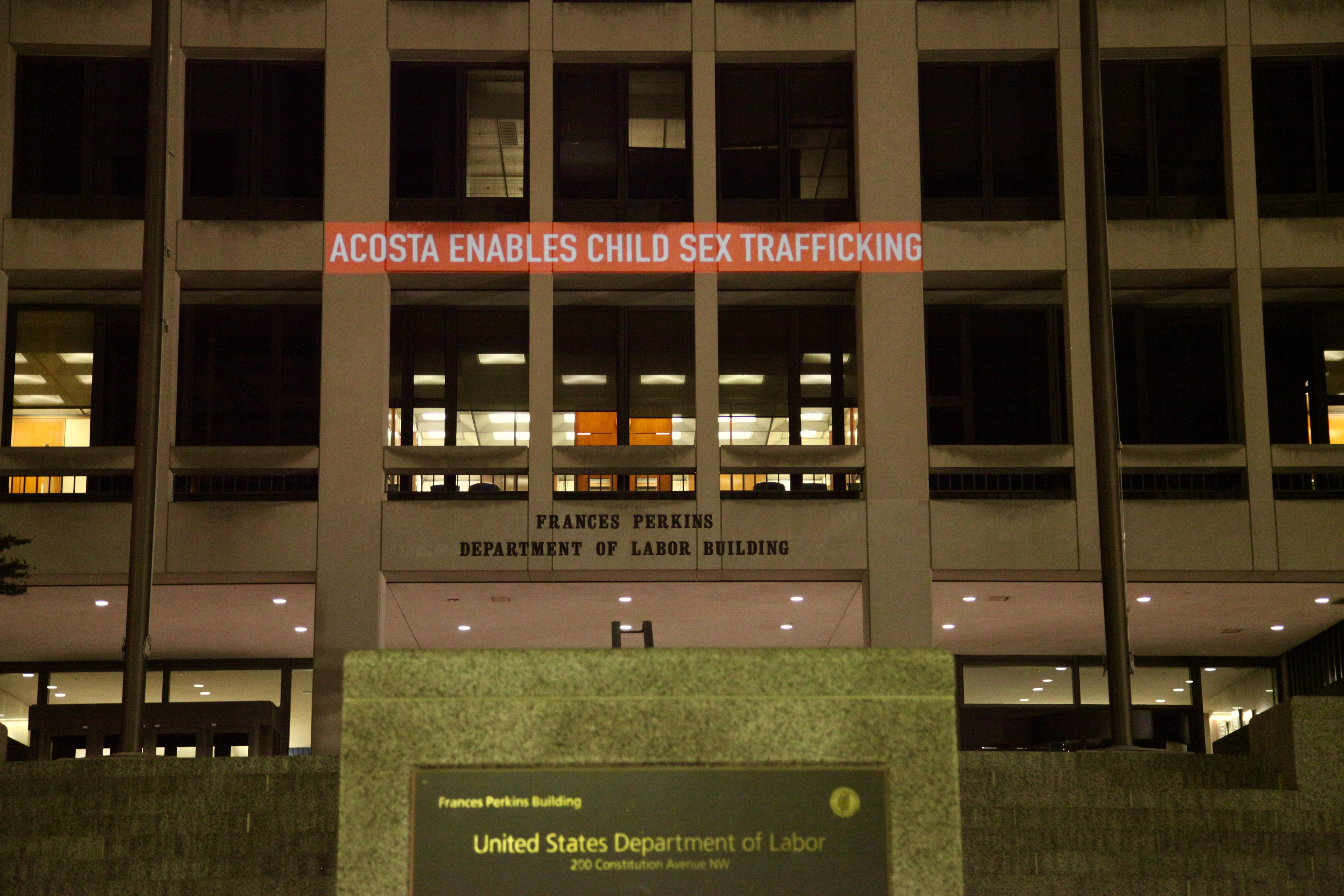 Light projection onto U.S. Department of Labor building reading, "Acosta enables child sex trafficking."