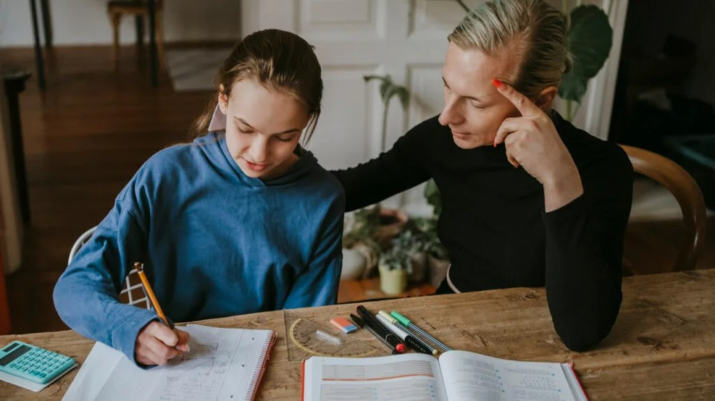 An adult helping a child with homework at a table-2
