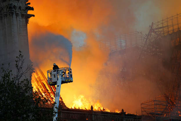 Slide 12 of 31: A fire fighter uses a hose as Notre Dame cathedral is burning in Paris, Monday, April 15, 2019. A catastrophic fire engulfed the upper reaches of Paris' soaring Notre Dame Cathedral as it was undergoing renovations Monday, threatening one of the greatest architectural treasures of the Western world as tourists and Parisians looked on aghast from the streets below. (AP Photo/Francois Mori)