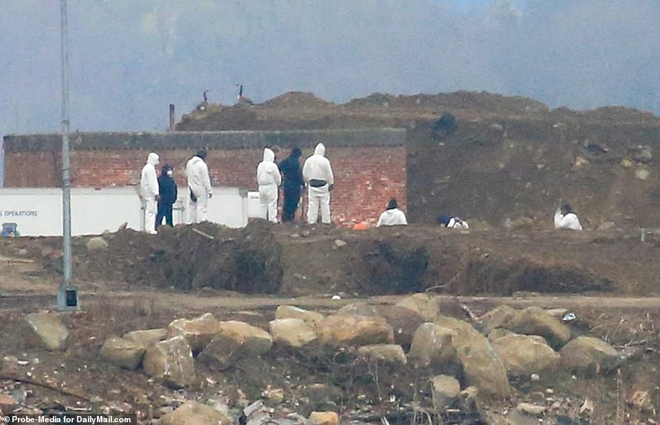 The majority of those digging on Thursday were dressed in white, head-to-toe hazmat suits amid the coronavirus pandemic