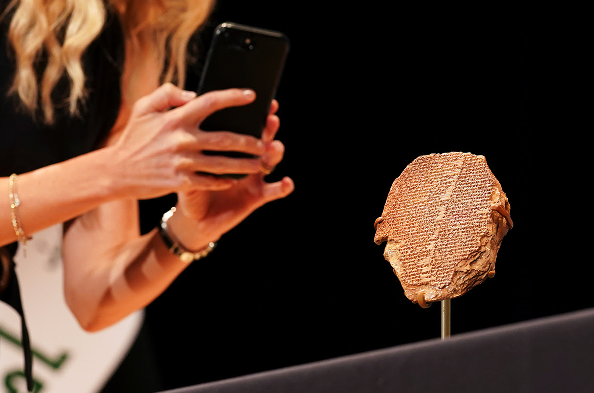 A woman photographs the Gilgamesh Dream Tablet during a ceremony hosted by the Smithsonian Institution to repatriate the antiquity to Iraq, in Washington U.S., September 23, 2021