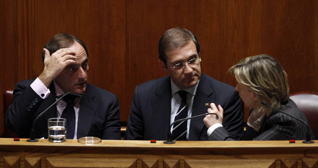El primer ministro de Portugal , Pedro Passos Coelho, habla con la ministra de Finanzas, María Luis Albuquerque, y y el viceministro Paulo Portas durante la votación del Presupuesto luso de 2014.