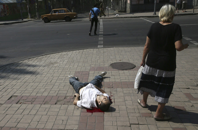 Una mujer permanece junto al cuerpo sin vida de un hombre tras un ataque del ejército ucraniano en el centro de Donetsk.