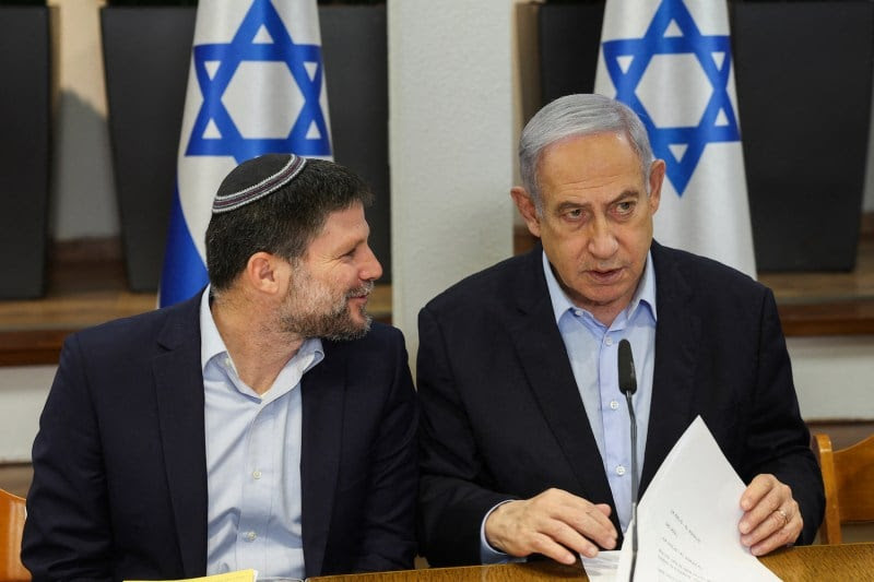 Israeli Prime Minister Benjamin Netanyahu (R) and Finance Minister Bezalel Smotrich attend the weekly cabinet meeting at the Defense Ministry in Tel Aviv.