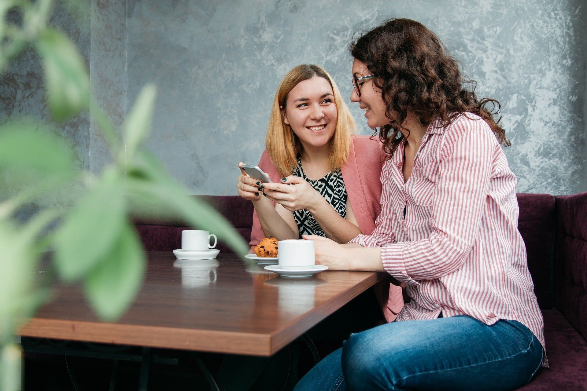 Dos mujeres en un café mirando un teléfono móvil