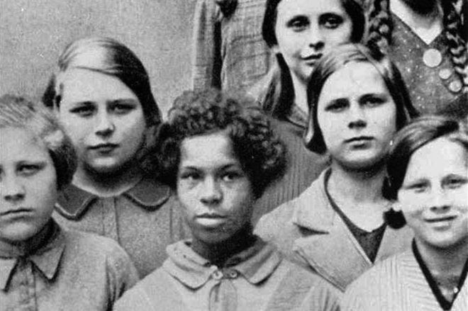 foto de garota negra cercada por garotas brancas, usada em palestras sobre genética na Academia Estadual de Raça e Saúde em Dresden, Alemanha, 1936.